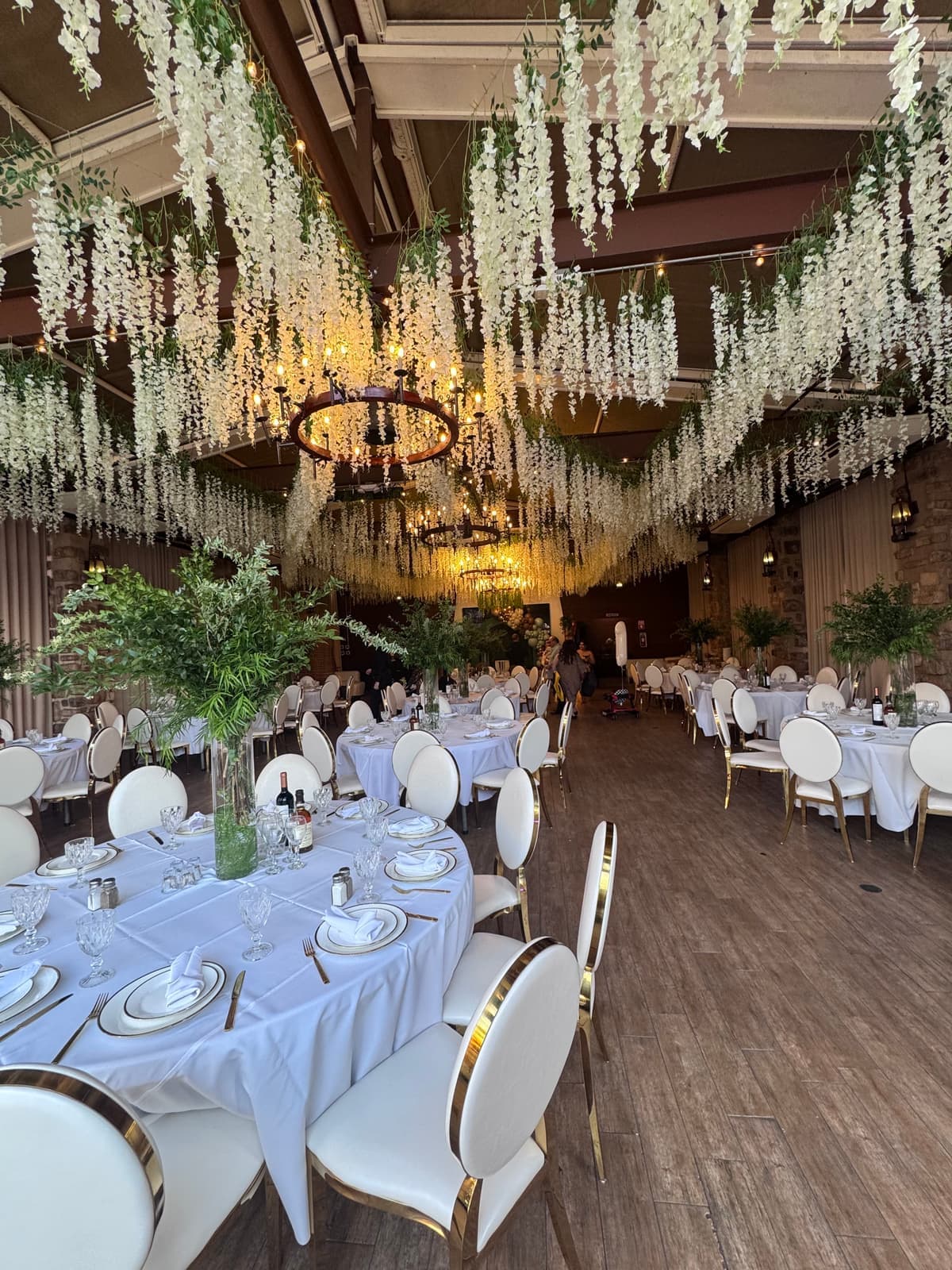 Banquet hall with cascading florals and round tables set for a reception