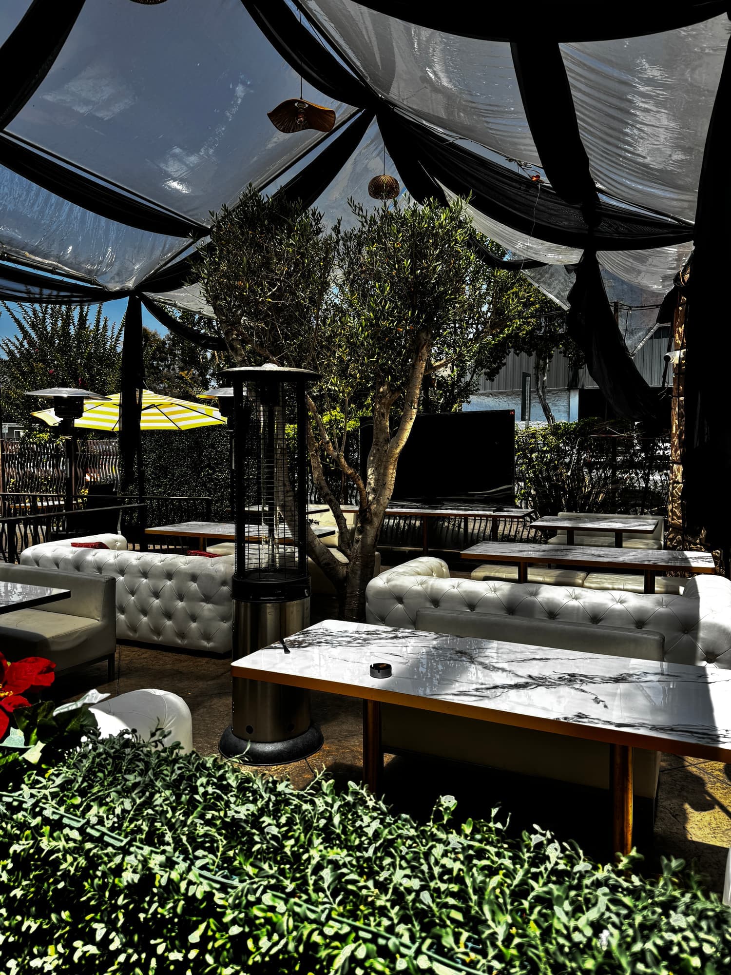 Phoenicia covered patio lounge seating with patio heaters and greenery